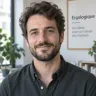 Portrait d’un homme d’une trentaine d’années, barbe courte, pull gris, devant un fond clair